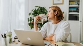 Seorang wanita modern sedang fokus meninjau laporan keuangan di laptopnya, menunjukkan dedikasinya dalam mengelola aset demi masa depan yang terencana dengan baik. Gambar ini merefleksikan pentingnya kemandirian finansial bagi perempuan dalam mencapai tujuan hidup mereka.