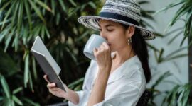 Seorang wanita menikmati secangkir teh hangat sambil membaca buku di pagi hari yang tenang, mencerminkan salah satu ide me time yang efektif untuk memulai hari dengan pikiran jernih. Momen pribadi seperti ini sangat penting untuk menjaga keseimbangan mental di tengah kesibukan sehari-hari.