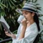 Seorang wanita menikmati secangkir teh hangat sambil membaca buku di pagi hari yang tenang, mencerminkan salah satu ide me time yang efektif untuk memulai hari dengan pikiran jernih. Momen pribadi seperti ini sangat penting untuk menjaga keseimbangan mental di tengah kesibukan sehari-hari.