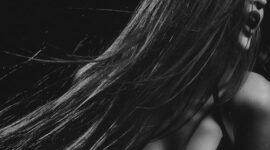 Seorang wanita dengan gaya rambut berlapis lembut yang terinspirasi dari era 90-an namun diperbarui dengan teknik pewarnaan balayage modern, menonjolkan dimensi dan tekstur alami rambutnya. Gaya ini sangat diminati karena memberikan volume tanpa kesan kaku.
