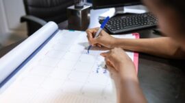 Seorang perempuan sedang menandai kalendernya, menunjukkan kebiasaan melacak siklus haid yang merupakan bagian penting dari pemahaman kesehatan reproduksi. Aktivitas ini membantu mengidentifikasi pola dan potensi masalah sejak dini.