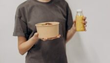 Seorang remaja perempuan sedang menikmati semangkuk salad buah segar, menunjukkan pentingnya asupan nutrisi seimbang untuk mendukung aktivitas sehari-hari dan tumbuh kembangnya.