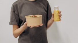 Seorang remaja perempuan sedang menikmati semangkuk salad buah segar, menunjukkan pentingnya asupan nutrisi seimbang untuk mendukung aktivitas sehari-hari dan tumbuh kembangnya.