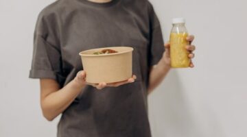 Seorang remaja perempuan sedang menikmati semangkuk salad buah segar, menunjukkan pentingnya asupan nutrisi seimbang untuk mendukung aktivitas sehari-hari dan tumbuh kembangnya.