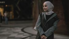 Seorang perempuan berhijab tampil stylish dengan paduan warna monokrom dan siluet longgar, mencerminkan tren busana muslimah yang mengutamakan kenyamanan dan keanggunan.