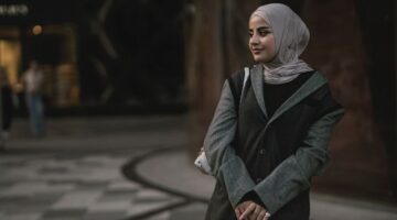 Seorang perempuan berhijab tampil stylish dengan paduan warna monokrom dan siluet longgar, mencerminkan tren busana muslimah yang mengutamakan kenyamanan dan keanggunan.