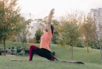 Seorang wanita melakukan meditasi ringan di taman kota, menunjukkan bagaimana keseimbangan mental dapat ditemukan di tengah hiruk pikuk perkotaan. Aktivitas ini menjadi salah satu kunci penting dalam membangun gaya hidup sehat yang menyeluruh.