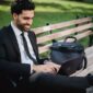 Seorang profesional tampak tersenyum lega setelah menutup laptopnya, di sampingnya ada cangkir kopi dan buku yang siap menemaninya menikmati waktu pribadi. Gambar ini merefleksikan pentingnya membatasi jam kerja untuk meraih keseimbangan hidup yang optimal.
