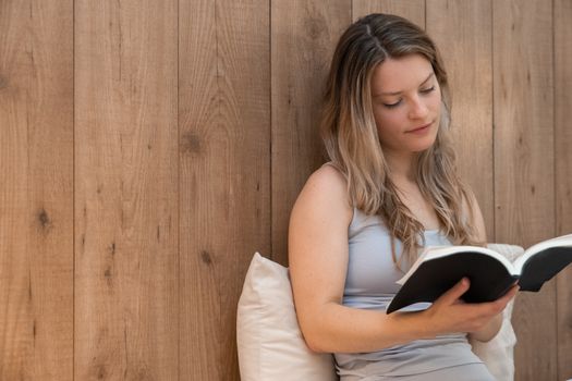 Seorang wanita menikmati momen tenang membaca buku di rumah, menunjukkan pentingnya meluangkan waktu untuk diri sendiri demi menjaga kesehatan mental di tengah kesibukan. Suasana nyaman ini mencerminkan ide me time yang efektif tanpa perlu keluar dari hunian pribadi.