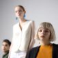 Seorang wanita berjalan dengan percaya diri mengenakan setelan berwarna hijau limau yang mencolok, dipadukan dengan tas tangan mini dan sepatu platform, merepresentasikan tren fashion wanita terkini di tahun 2026 yang mengedepankan warna vibran dan siluet berani.