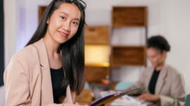 Seorang wanita profesional Indonesia tersenyum percaya diri di lingkungan kantor modern, merefleksikan kesuksesan dan keseimbangan dalam kariernya. Ia menunjukkan bahwa dengan strategi yang tepat, setiap wanita bisa mencapai potensi penuhnya.
