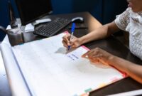 Seorang wanita sedang menyusun jadwal dan daftar prioritas dalam buku catatan, menunjukkan komitmennya terhadap manajemen waktu yang efektif untuk mencapai keseimbangan hidup. Gambar ini merefleksikan upaya proaktif dalam merencanakan hari demi produktivitas yang berkelanjutan.