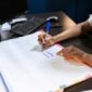 Seorang wanita sedang menyusun jadwal dan daftar prioritas dalam buku catatan, menunjukkan komitmennya terhadap manajemen waktu yang efektif untuk mencapai keseimbangan hidup. Gambar ini merefleksikan upaya proaktif dalam merencanakan hari demi produktivitas yang berkelanjutan.