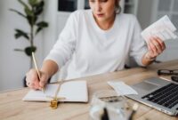 Seorang perempuan muda sedang fokus meninjau catatan keuangan dan anggaran bulanannya, menunjukkan dedikasi dalam mengelola setiap detail pemasukan serta pengeluaran demi mencapai tujuan finansial pribadinya. Aktivitas ini menggambarkan langkah penting menuju kemandirian ekonomi.