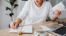 Seorang perempuan muda sedang fokus meninjau catatan keuangan dan anggaran bulanannya, menunjukkan dedikasi dalam mengelola setiap detail pemasukan serta pengeluaran demi mencapai tujuan finansial pribadinya. Aktivitas ini menggambarkan langkah penting menuju kemandirian ekonomi.
