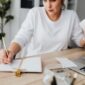 Seorang perempuan muda sedang fokus meninjau catatan keuangan dan anggaran bulanannya, menunjukkan dedikasi dalam mengelola setiap detail pemasukan serta pengeluaran demi mencapai tujuan finansial pribadinya. Aktivitas ini menggambarkan langkah penting menuju kemandirian ekonomi.