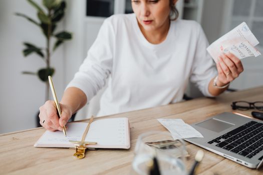 Seorang perempuan muda sedang fokus meninjau catatan keuangan dan anggaran bulanannya, menunjukkan dedikasi dalam mengelola setiap detail pemasukan serta pengeluaran demi mencapai tujuan finansial pribadinya. Aktivitas ini menggambarkan langkah penting menuju kemandirian ekonomi.