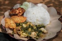 Sebuah hidangan nasi goreng kampung yang disajikan dengan telur mata sapi, kerupuk, dan acar, tampak begitu menggoda selera dengan taburan bawang goreng. Hidangan ini menunjukkan bagaimana makanan rumahan yang sederhana bisa diolah menjadi sajian istimewa yang lezat dan praktis.