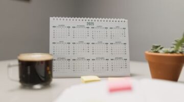 Seorang wanita tengah merencanakan jadwal hariannya menggunakan kalender dan catatan, menunjukkan dedikasi pada manajemen waktu yang terstruktur. Gambar ini merepresentasikan pentingnya perencanaan dan fokus dalam mencapai produktivitas maksimal.