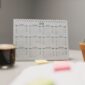 Seorang wanita tengah merencanakan jadwal hariannya menggunakan kalender dan catatan, menunjukkan dedikasi pada manajemen waktu yang terstruktur. Gambar ini merepresentasikan pentingnya perencanaan dan fokus dalam mencapai produktivitas maksimal.