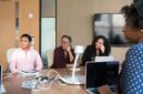 Seorang wanita profesional berdiskusi dengan mentornya di lingkungan kantor modern, menunjukkan kolaborasi dan dukungan dalam pengembangan karier. Gambar ini merepresentasikan pentingnya bimbingan dan pembelajaran berkelanjutan bagi wanita dalam meraih sukses.