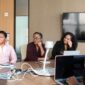 Seorang wanita profesional berdiskusi dengan mentornya di lingkungan kantor modern, menunjukkan kolaborasi dan dukungan dalam pengembangan karier. Gambar ini merepresentasikan pentingnya bimbingan dan pembelajaran berkelanjutan bagi wanita dalam meraih sukses.