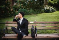 Seorang profesional tampak tersenyum sambil melakukan yoga di tengah taman kota, melambangkan harmoni antara pekerjaan dan waktu pribadi. Keseimbangan hidup dan kerja esensial untuk menjaga kesehatan mental dan produktivitas.