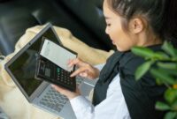 Seorang perempuan Indonesia dengan penuh konsentrasi memeriksa laporan keuangan di laptopnya, merefleksikan dedikasi dalam mengelola masa depan finansialnya. Gambar ini menunjukkan kemandirian dan kecakapan perempuan dalam mengambil kendali atas keputusan keuangannya.