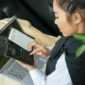 Seorang perempuan Indonesia dengan penuh konsentrasi memeriksa laporan keuangan di laptopnya, merefleksikan dedikasi dalam mengelola masa depan finansialnya. Gambar ini menunjukkan kemandirian dan kecakapan perempuan dalam mengambil kendali atas keputusan keuangannya.