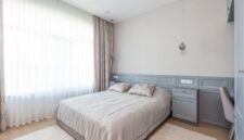 Kamar tidur minimalis dengan dominasi warna netral dan pencahayaan alami yang melimpah, menciptakan suasana tenang dan lapang. Desain ini mengutamakan fungsi esensial dan keindahan sederhana untuk mendukung istirahat yang berkualitas.