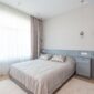 Kamar tidur minimalis dengan dominasi warna netral dan pencahayaan alami yang melimpah, menciptakan suasana tenang dan lapang. Desain ini mengutamakan fungsi esensial dan keindahan sederhana untuk mendukung istirahat yang berkualitas.
