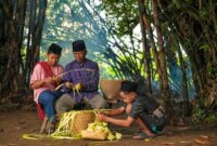 Seorang nenek mendongeng kepada cucu-cucunya di teras rumah pedesaan, menggambarkan tradisi lisan yang masih hidup di banyak daerah Indonesia. Momen hangat ini menunjukkan bagaimana cerita rakyat diwariskan secara personal dari generasi ke generasi.