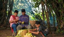 Seorang nenek mendongeng kepada cucu-cucunya di teras rumah pedesaan, menggambarkan tradisi lisan yang masih hidup di banyak daerah Indonesia. Momen hangat ini menunjukkan bagaimana cerita rakyat diwariskan secara personal dari generasi ke generasi.