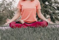 Seorang wanita sedang bermeditasi dengan tenang di tengah hijaunya alam, merefleksikan esensi gaya hidup "slow living" yang menenangkan jiwa dan pikiran dari hiruk pikuk kehidupan. Pemandangan ini menggambarkan ketenangan serta keseimbangan yang bisa dicapai melalui kesadaran penuh terhadap diri sendiri dan lingkungan sekitar.