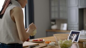 Seorang koki profesional tampak sibuk mengatur berbagai bahan masakan di meja dapur, menggambarkan konsep persiapan matang dalam manajemen waktu yang efisien. Foto ini merefleksikan pentingnya *mise en place* dalam merencanakan jadwal harian untuk mencapai produktivitas maksimal.